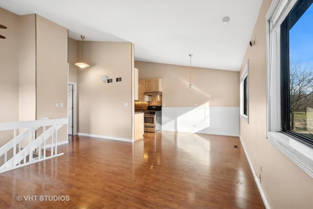 empty room with dark hardwood / wood-style flooring, a wealth of natural light, and vaulted ceiling