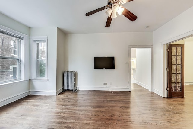 unfurnished living room featuring ceiling fan, radiator heating unit, and hardwood / wood-style floors