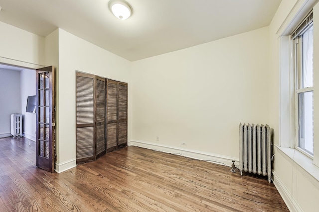 unfurnished bedroom featuring radiator, a closet, and hardwood / wood-style floors