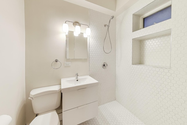 bathroom with tile patterned flooring, a tile shower, vanity, and toilet