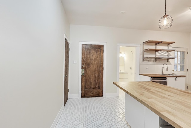 kitchen featuring sink, decorative light fixtures, dishwasher, white cabinets, and butcher block counters