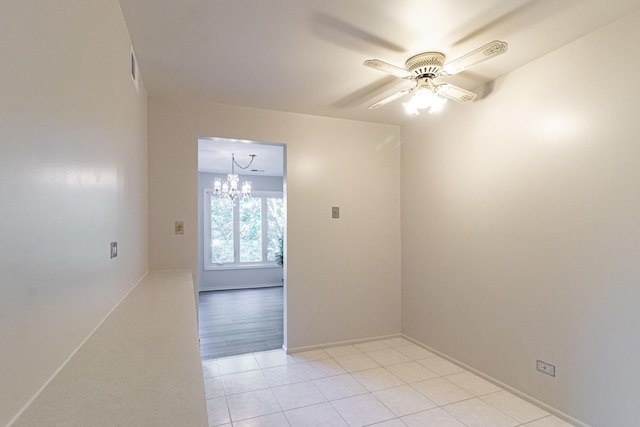 unfurnished room featuring ceiling fan with notable chandelier and light tile patterned flooring