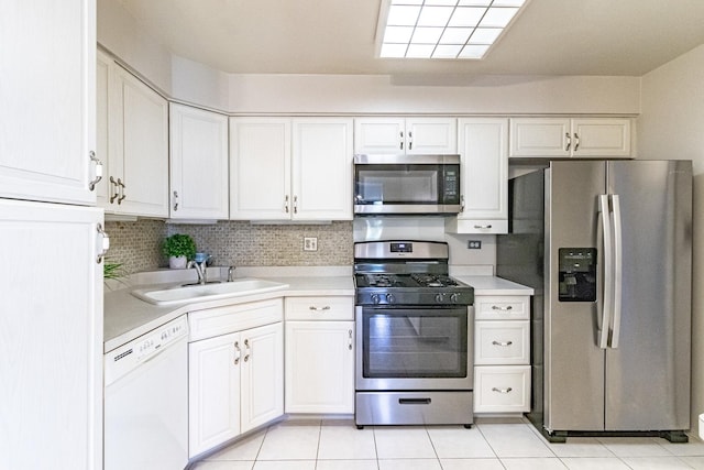 kitchen with tasteful backsplash, stainless steel appliances, sink, light tile patterned floors, and white cabinetry