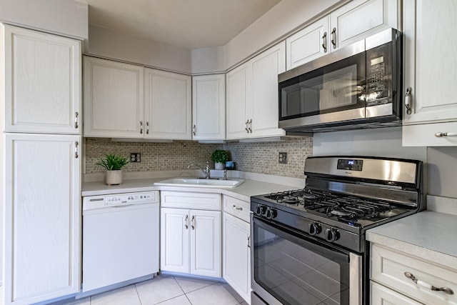 kitchen with tasteful backsplash, stainless steel appliances, sink, light tile patterned floors, and white cabinetry