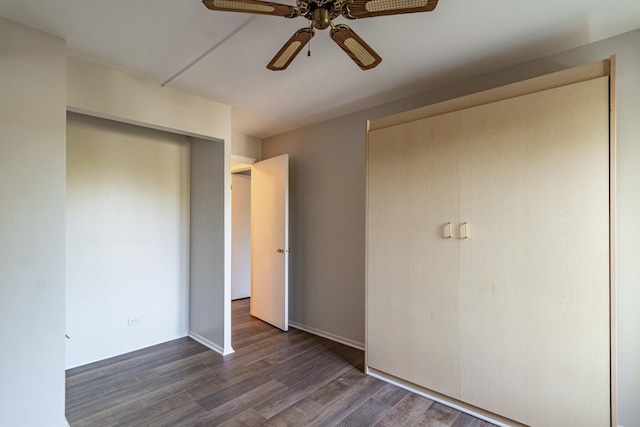 unfurnished bedroom with ceiling fan and dark wood-type flooring