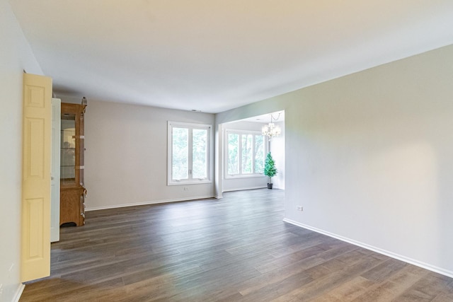 spare room featuring a chandelier and dark hardwood / wood-style floors