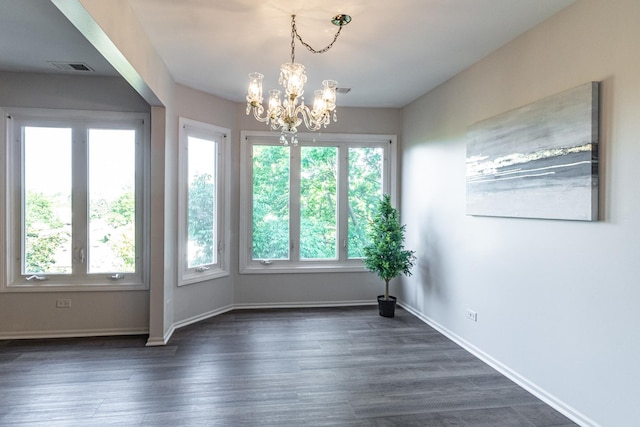 unfurnished room featuring dark wood-type flooring and an inviting chandelier