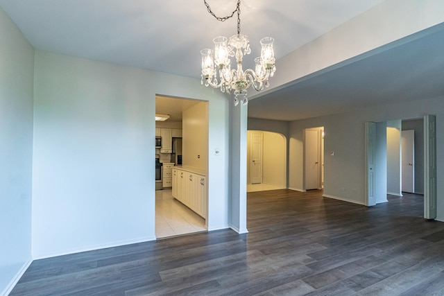 empty room with a chandelier and dark hardwood / wood-style floors