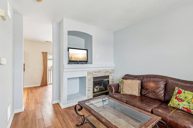 living room with a stone fireplace and light wood-type flooring