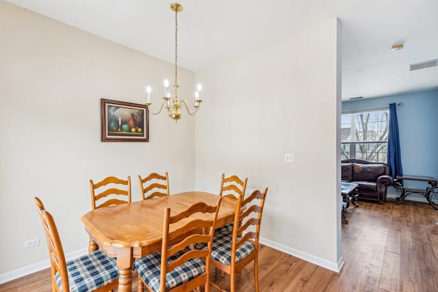 dining room with wood-type flooring and a notable chandelier