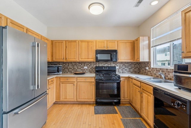 kitchen with light brown cabinets, black appliances, sink, light hardwood / wood-style flooring, and decorative backsplash