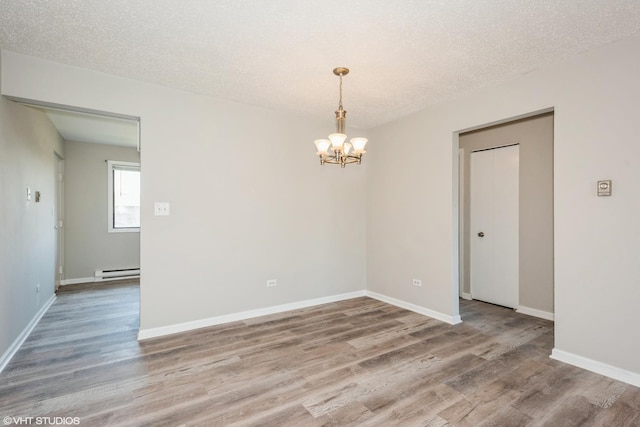 spare room with a notable chandelier, wood-type flooring, a textured ceiling, and baseboard heating