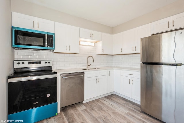 kitchen with tasteful backsplash, stainless steel appliances, sink, light hardwood / wood-style flooring, and white cabinets