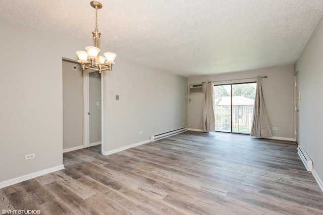 unfurnished room with a wall mounted AC, wood-type flooring, a chandelier, and a baseboard heating unit