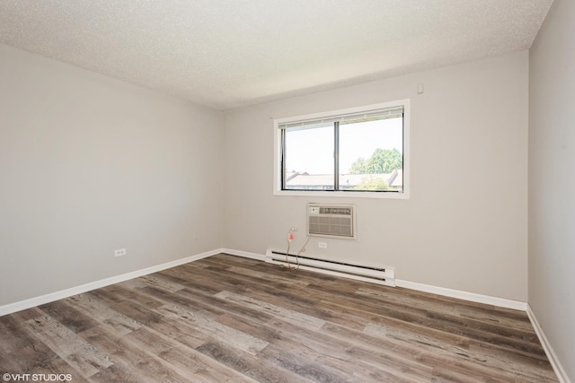 empty room with dark hardwood / wood-style flooring, a textured ceiling, a baseboard radiator, and an AC wall unit