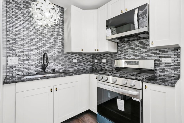 kitchen featuring appliances with stainless steel finishes, tasteful backsplash, dark stone counters, sink, and white cabinetry