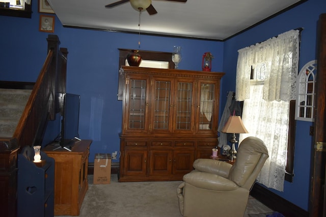 living area with a wealth of natural light, light carpet, and ceiling fan