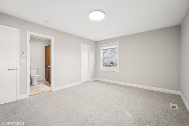 unfurnished bedroom featuring light carpet and ensuite bath