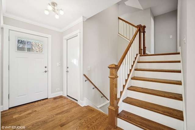 foyer featuring hardwood / wood-style floors, an inviting chandelier, and ornamental molding