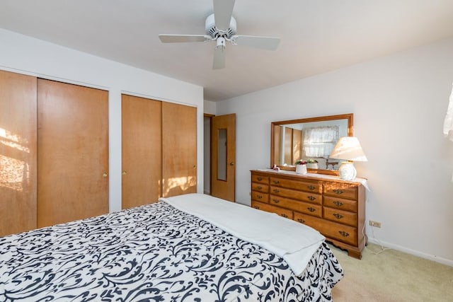 carpeted bedroom with ceiling fan and multiple closets