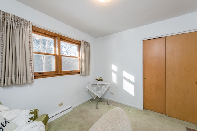 sitting room featuring a baseboard heating unit and light colored carpet