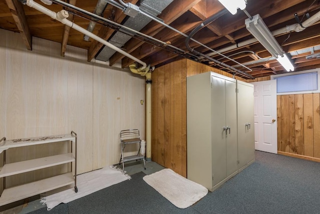 basement featuring carpet flooring and wood walls