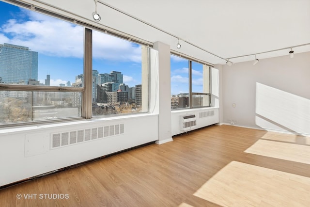 unfurnished sunroom with radiator and track lighting