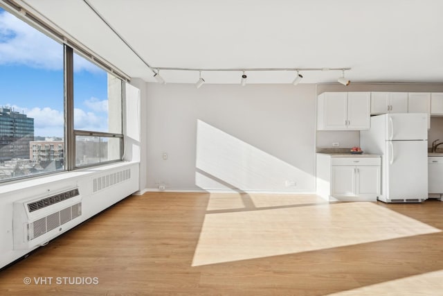 kitchen featuring white cabinets, white refrigerator, a wall unit AC, and light hardwood / wood-style flooring