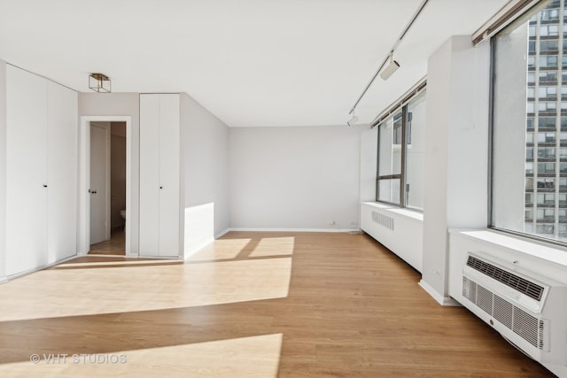 interior space with radiator heating unit, light hardwood / wood-style flooring, and track lighting