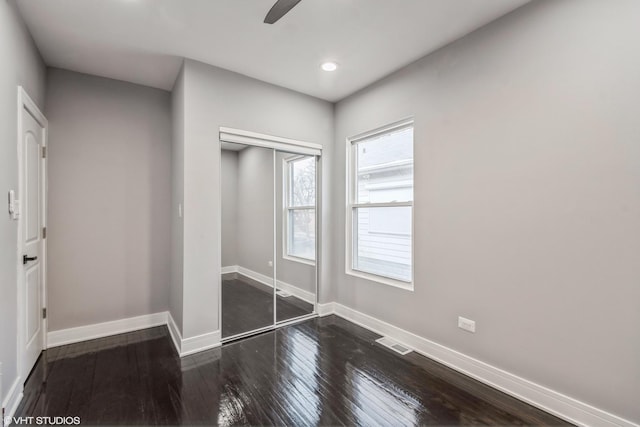 unfurnished bedroom with a closet, dark wood-type flooring, and ceiling fan