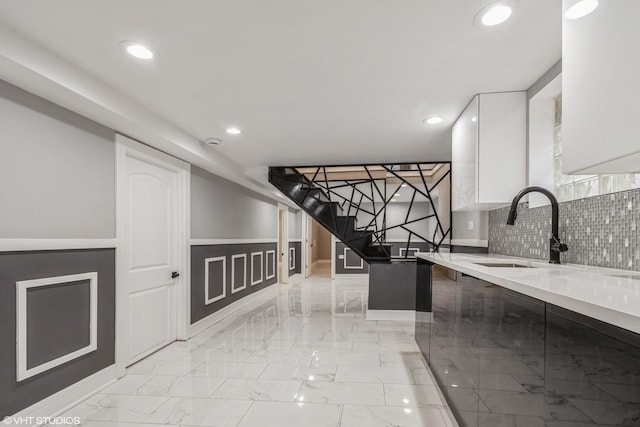 kitchen with tasteful backsplash, sink, and white cabinets