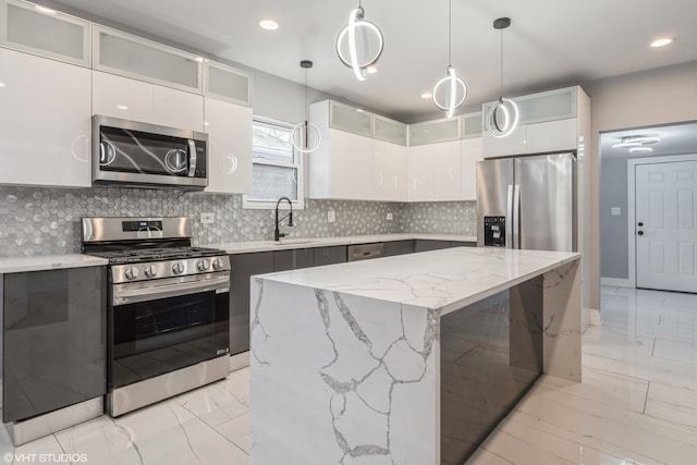 kitchen featuring white cabinets, a kitchen island, stainless steel appliances, and pendant lighting