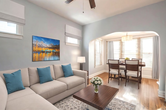 living room with light wood-type flooring and ceiling fan with notable chandelier