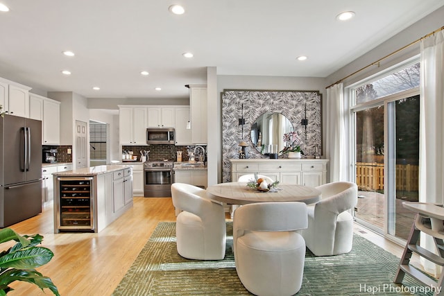 dining area featuring wine cooler, sink, and light wood-type flooring