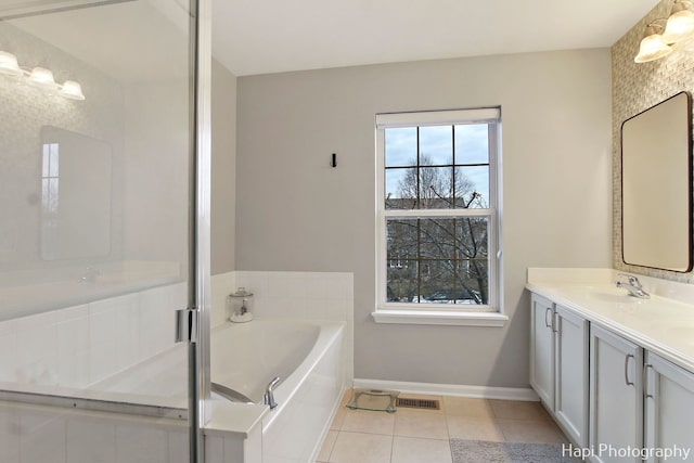 bathroom with tile patterned floors, a bathing tub, plenty of natural light, and vanity