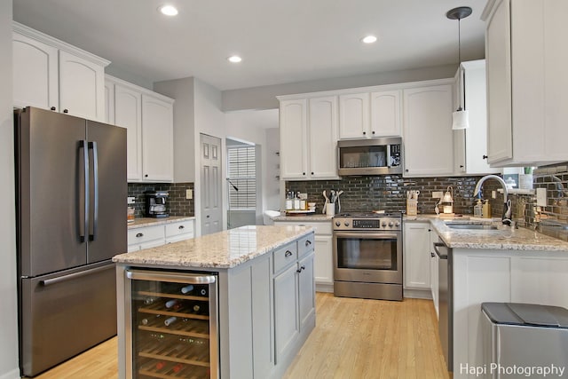 kitchen featuring a center island, wine cooler, decorative light fixtures, white cabinets, and appliances with stainless steel finishes