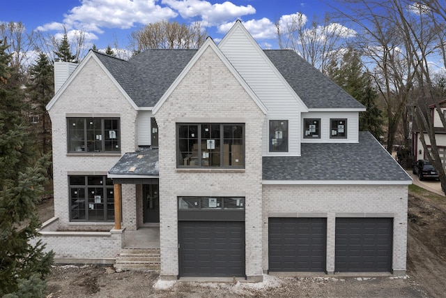 view of front of home featuring an attached garage, a shingled roof, and brick siding