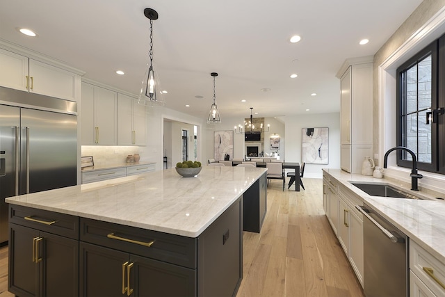 kitchen featuring sink, white cabinetry, light stone counters, a center island, and appliances with stainless steel finishes