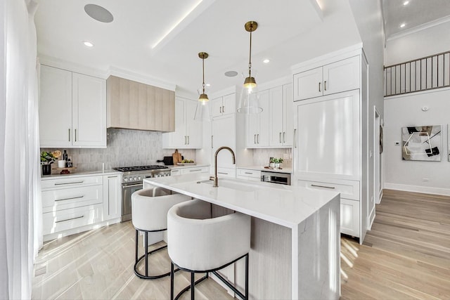 kitchen featuring white cabinetry, an island with sink, and high end stainless steel range