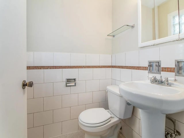 bathroom featuring toilet and tile walls