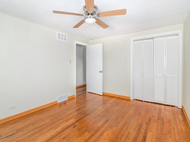 unfurnished bedroom with ceiling fan, light wood-type flooring, and a closet