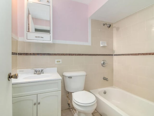 full bathroom with toilet, vanity, tile walls, and tiled shower / bath