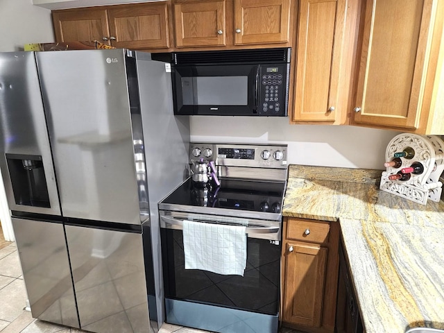 kitchen featuring light tile patterned flooring, light stone counters, and stainless steel appliances