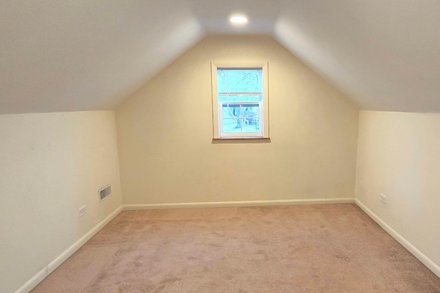 bonus room with lofted ceiling and light carpet