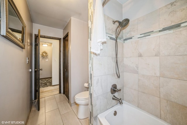 bathroom with toilet and tiled shower / bath