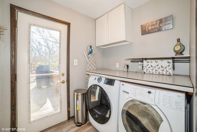 laundry area with washing machine and clothes dryer, cabinets, and light hardwood / wood-style floors