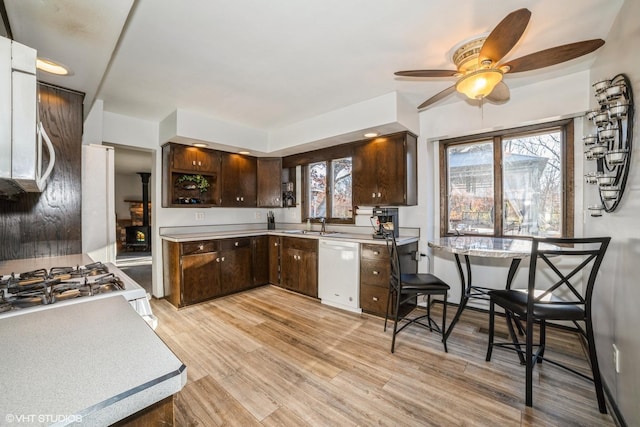 kitchen with light wood-type flooring, dark brown cabinets, white dishwasher, ceiling fan, and sink