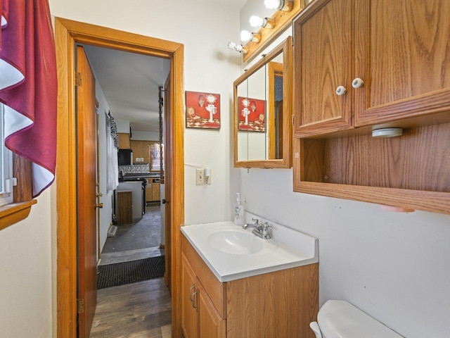 bathroom with hardwood / wood-style flooring, vanity, and toilet