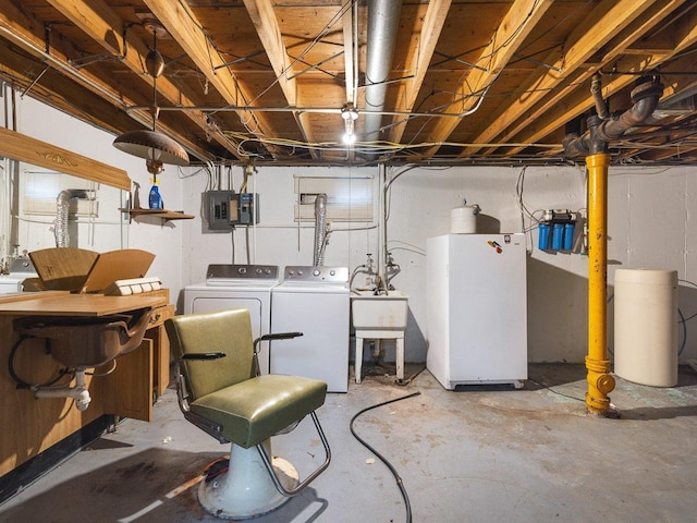 basement featuring washing machine and dryer, sink, and white fridge