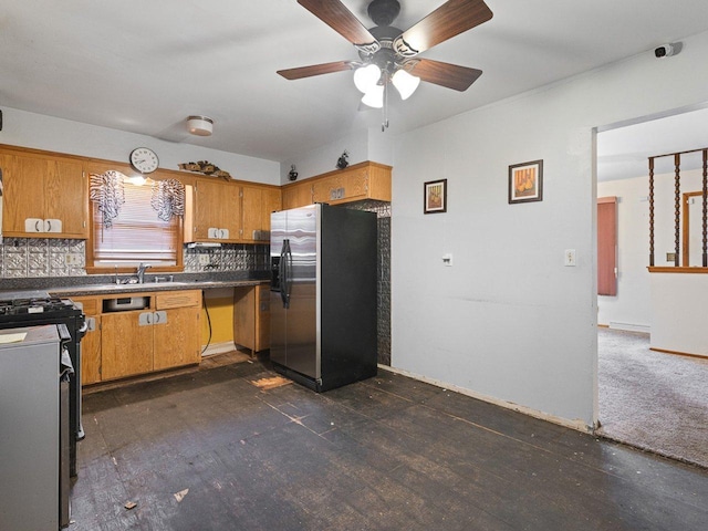 kitchen featuring stainless steel refrigerator with ice dispenser, backsplash, stove, ceiling fan, and sink